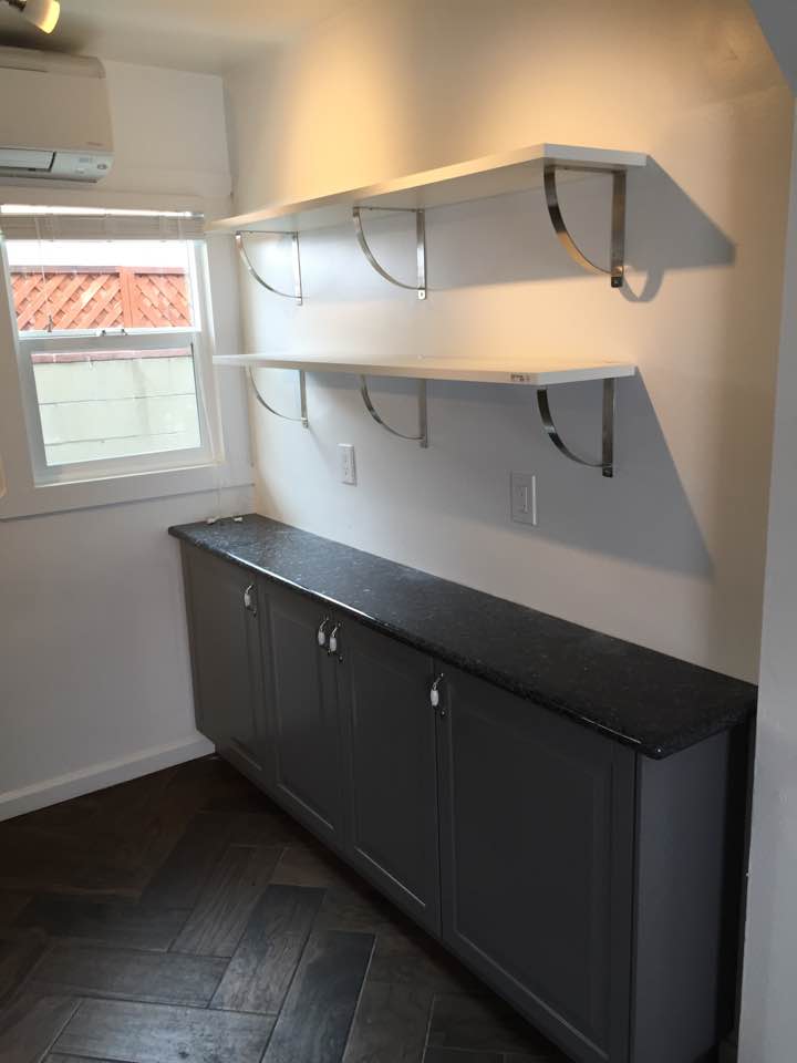 Minimalist kitchen shelves and cabinets with a window view.