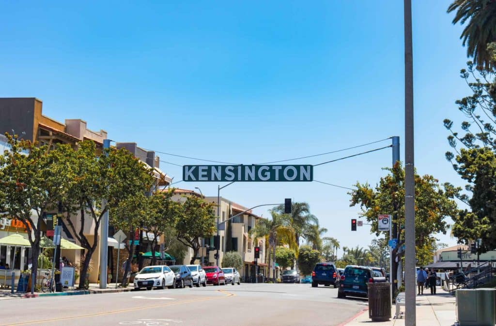 Street view of Kensington with a clear blue sky and hanging sign.